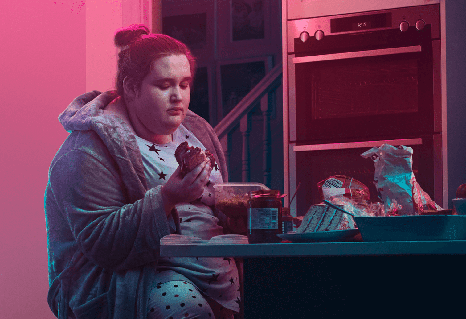 Girl sitting at kitchen counter and eating. Actor portrayal.